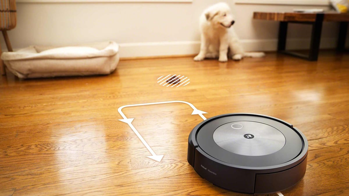 Um robô aspirador e um cachorro branco em um piso de madeira